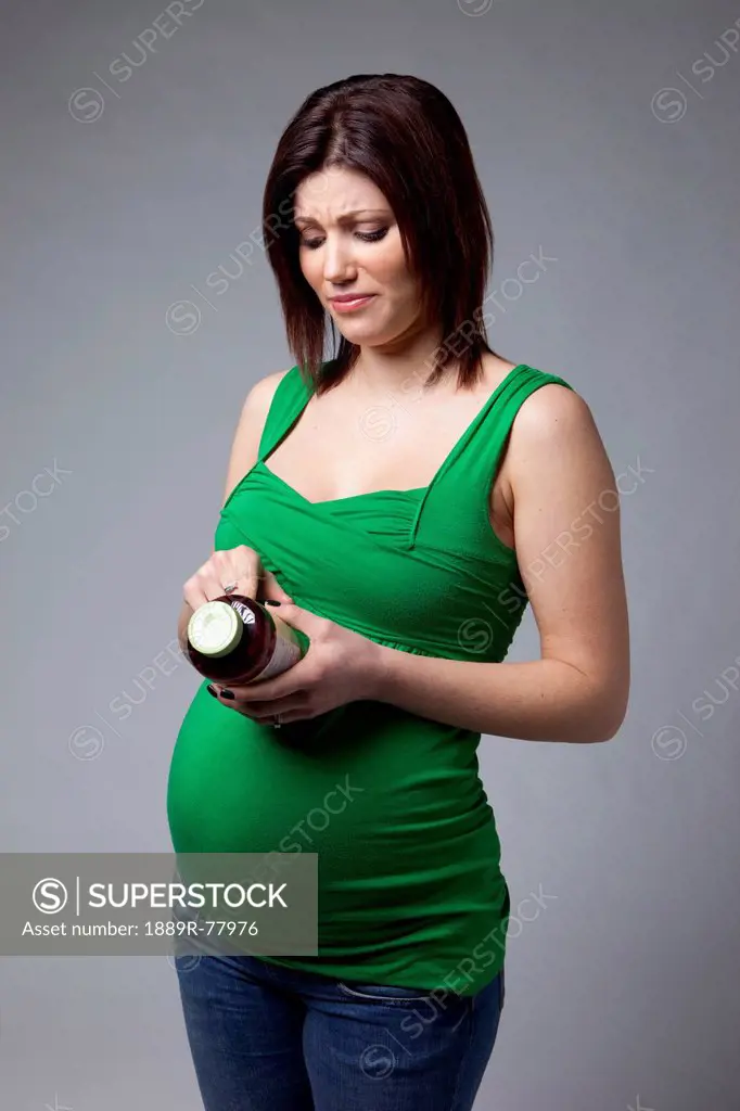 A pregnant woman reading the label on a bottle, edmonton alberta canada