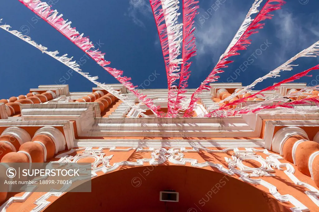 White and red streamers blowing in the wind strung above a building´s doorway, guatemala city guatemala