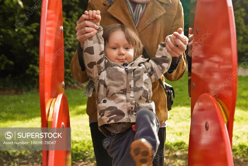 A Parent Holds A Young Child´s Hands As They Climb A Playground Structure, Thomastown County Kilkenny Ireland