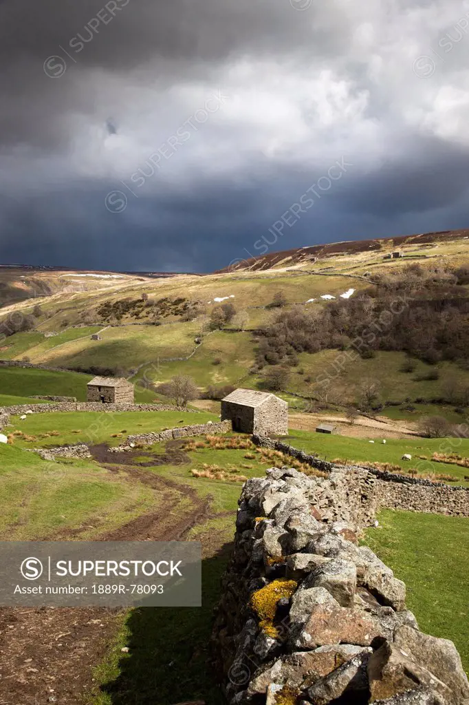 A stone wall curving through the landscape under storm clouds, swaledale england