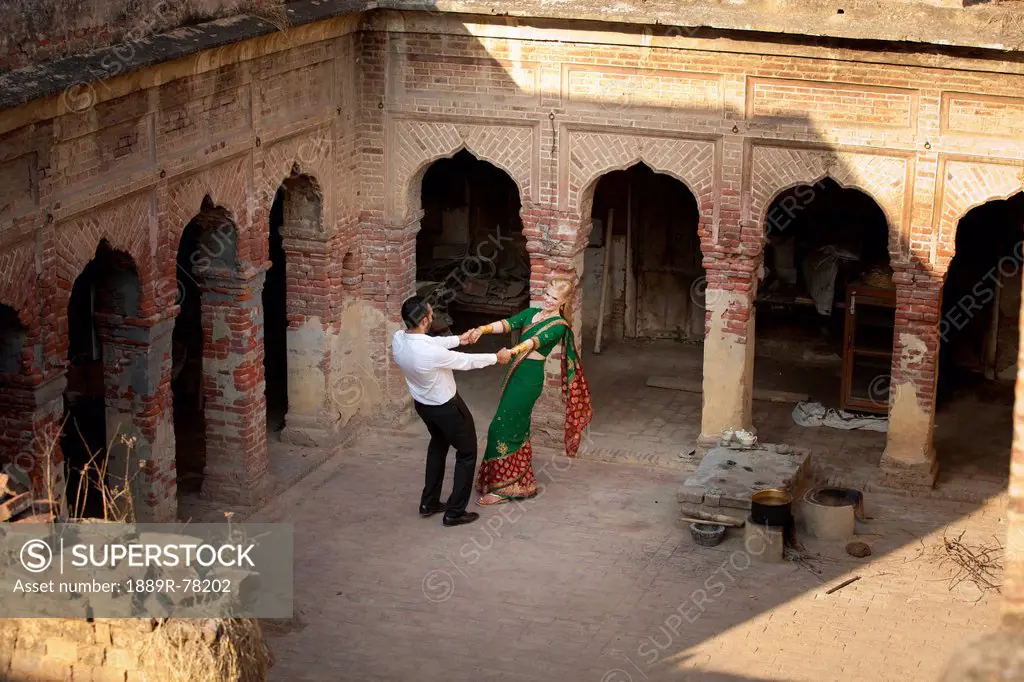 A mixed race couple dancing in a courtyard with her wearing a sari, ludhiana punjab india