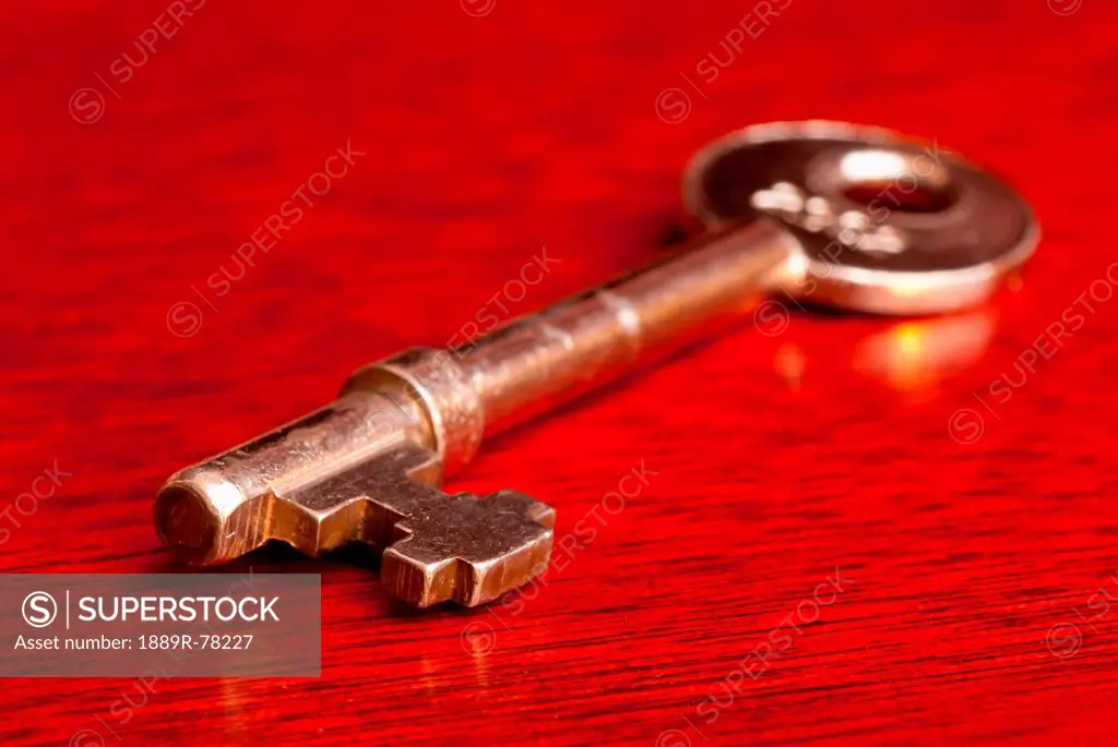 A Gold Key Sitting On A Red Table