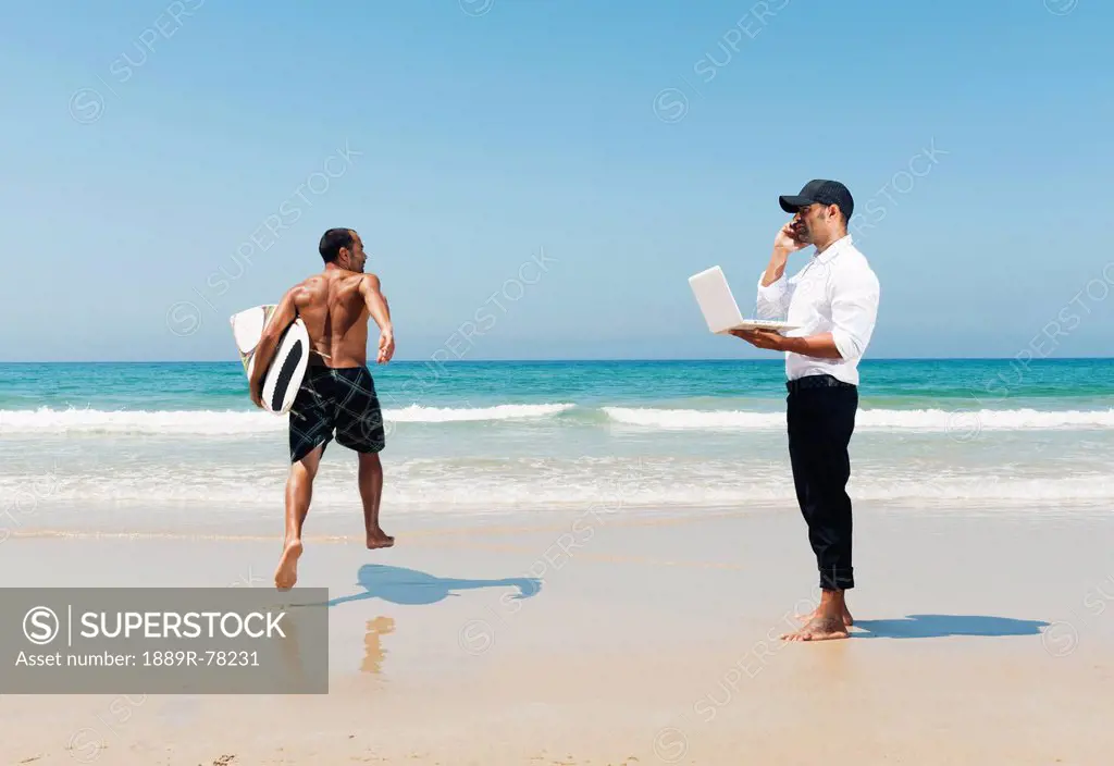 A Man Standing On A Beach Representing Himself With A Surfboard On Vacation And Working As A Businessman, Tarifa Cadiz Andalusia Spain