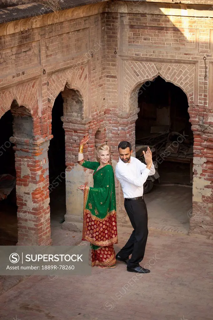 A mixed race couple dancing in a courtyard with her wearing a sari, ludhiana punjab india