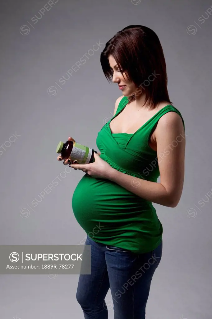 A pregnant woman reading the label on a bottle, edmonton alberta canada