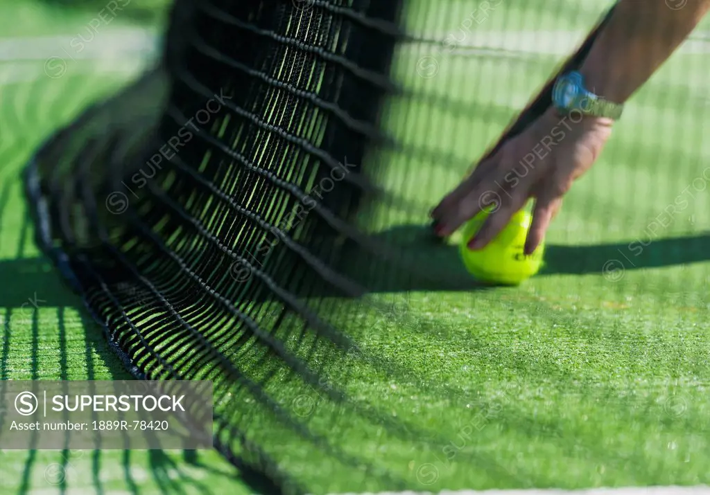 Retrieving a tennis ball by the net, tarifa cadiz andalusia spain
