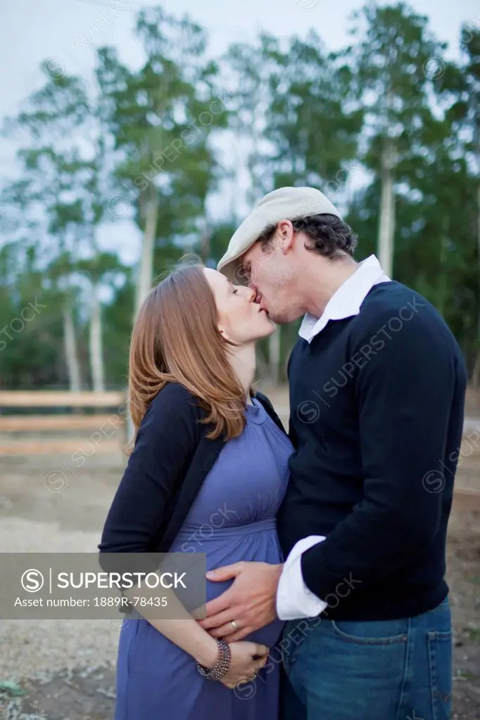 A couple kissing with their hands on her pregnant belly, sherwood park alberta canada