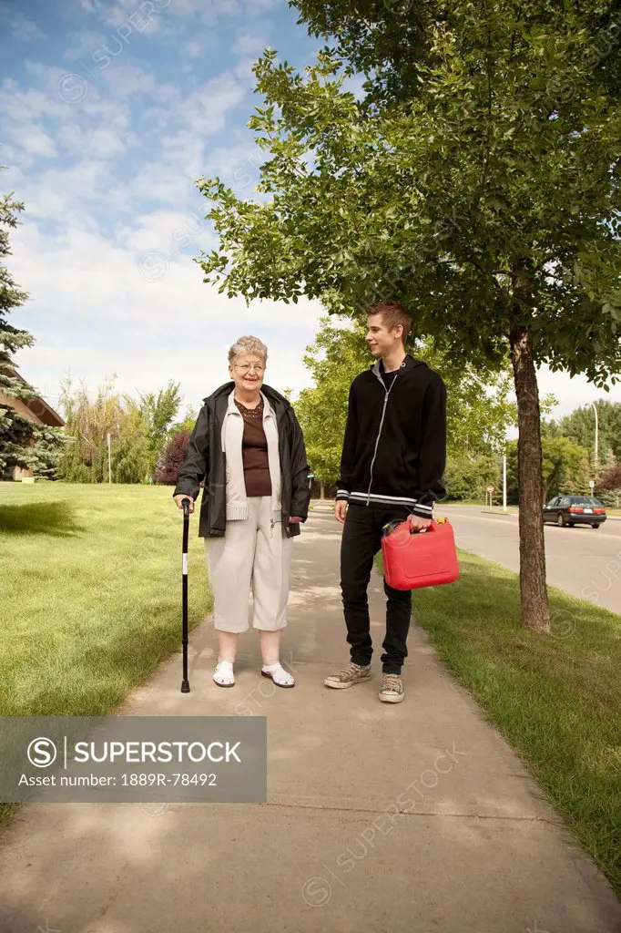 a senior woman walks and talks with a teenage boy, edmonton, alberta, canada