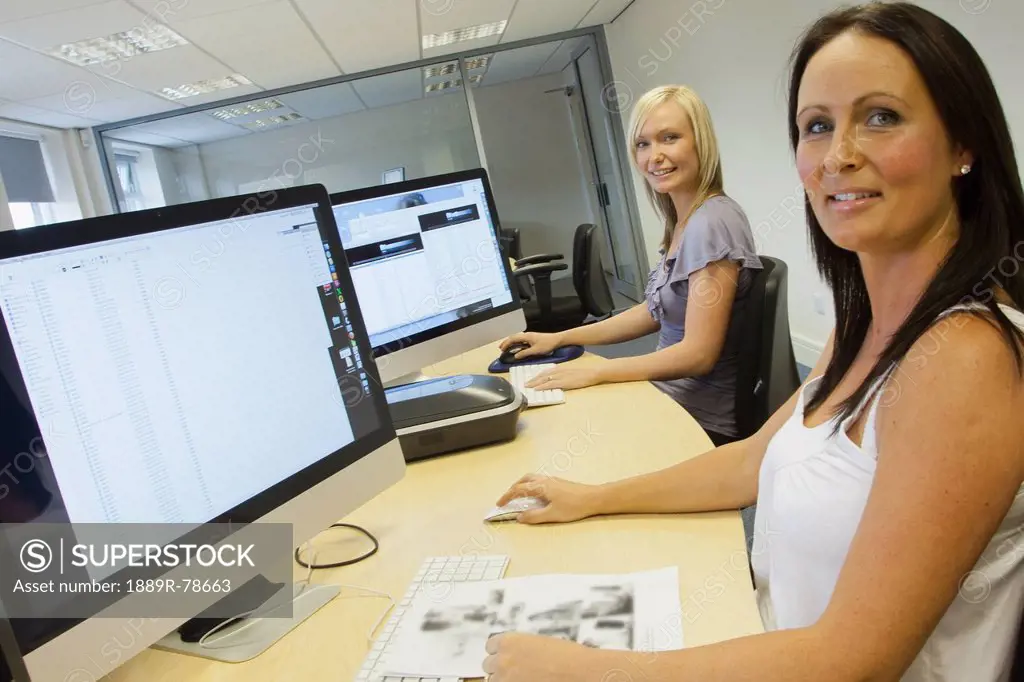 Two Young Women Sitting In Front Of Their Computer Monitors At Work, South Shields Tyne And Wear England
