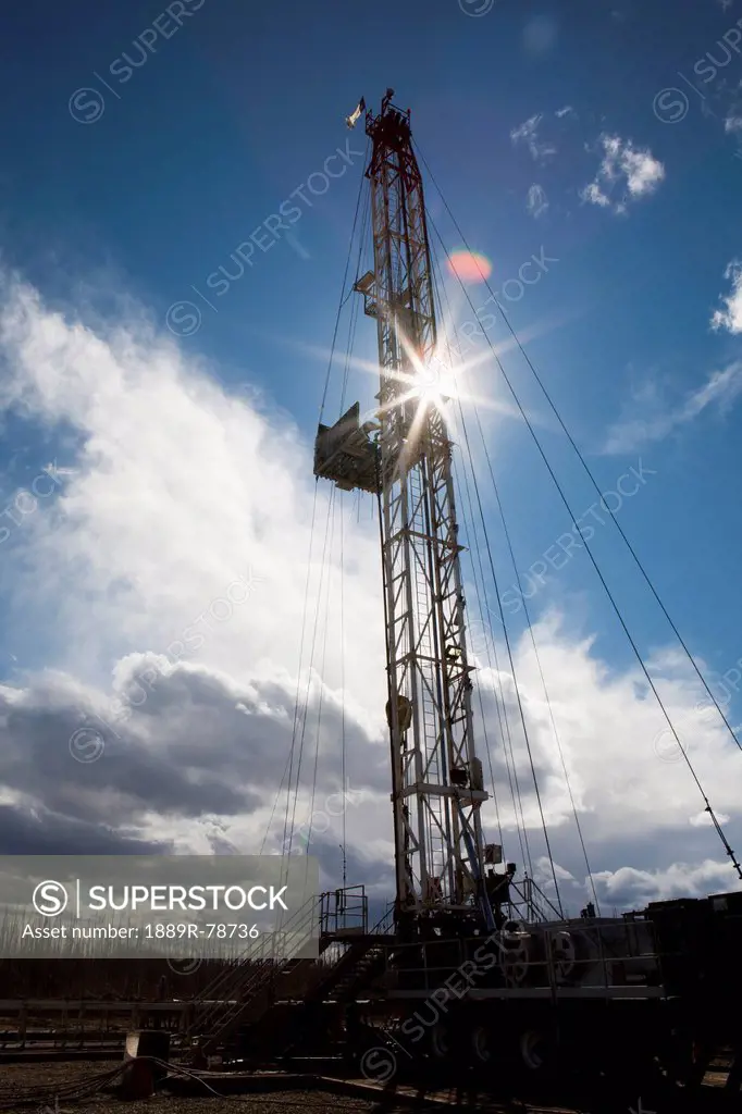 Silhouette of a drilling rig with sunburst blue sky and clouds near drayton valley, alberta canada