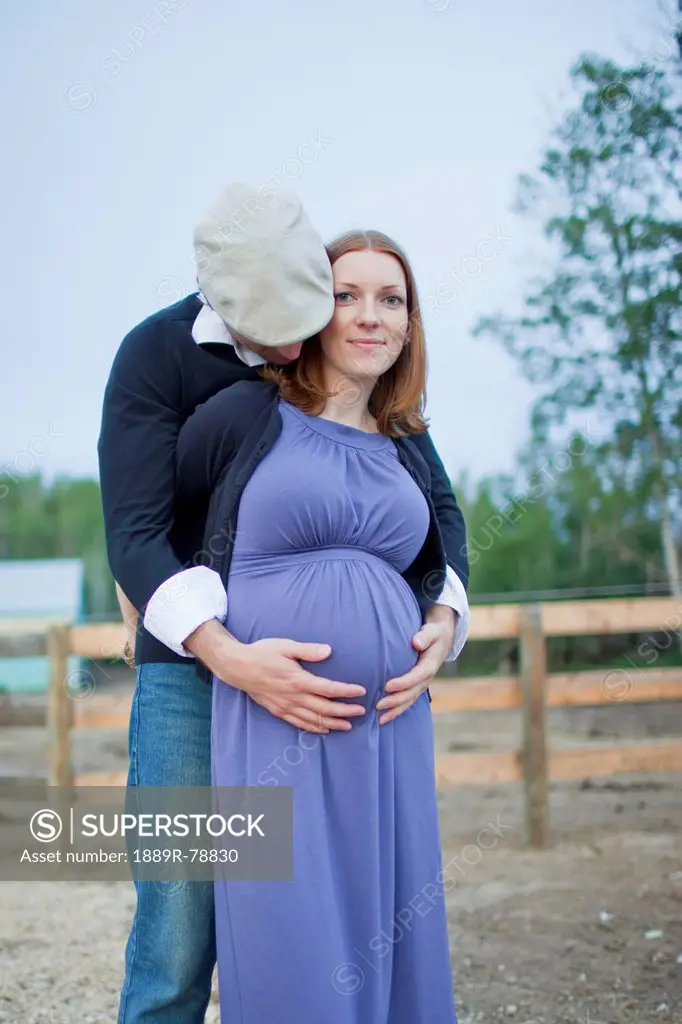 A husband embraces his wife and her pregnant belly, sherwood park alberta canada