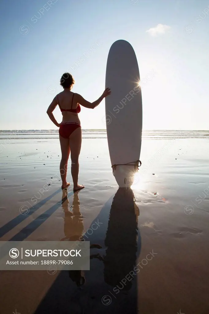 A woman holds her surfboard on playa santa teresa santa teresa beach in santa teresa and mal pais malpais on the nicoya peninsula, puntarenas province...