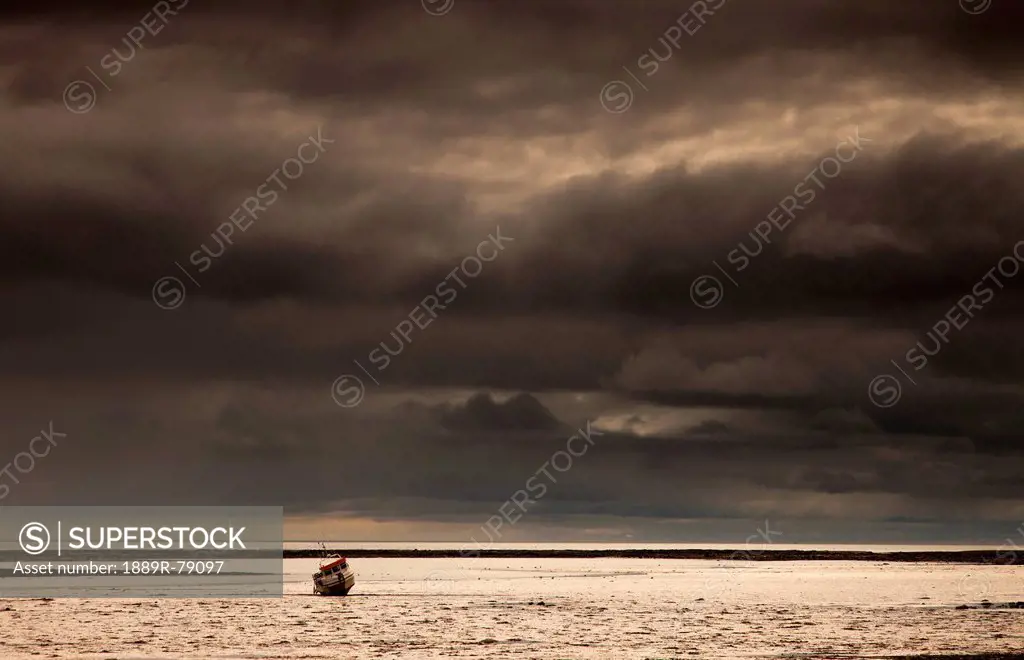 A fishing boat out in the water under dark storm clouds, boulmer northumberland england