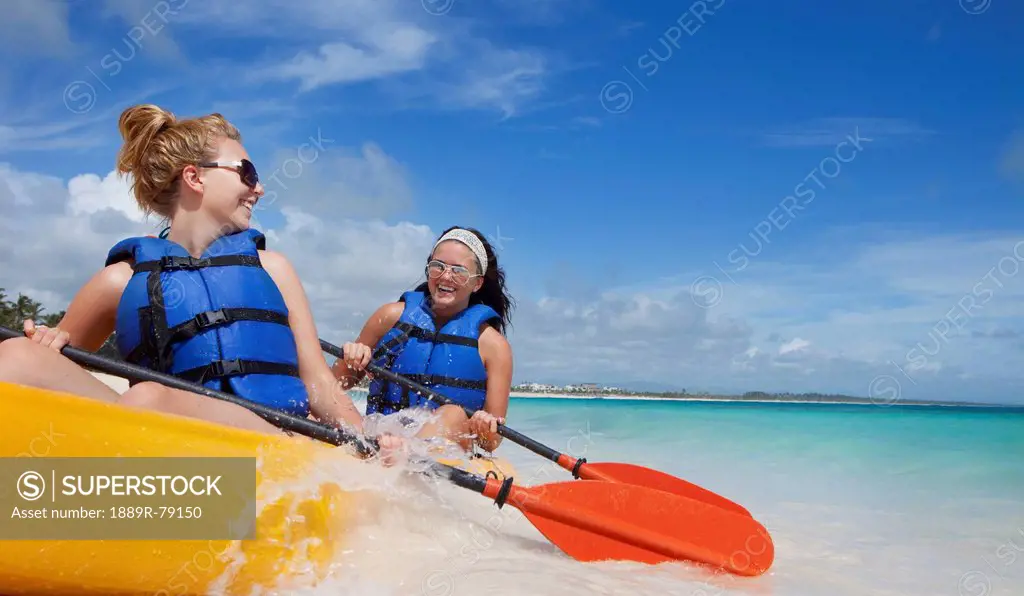 Two women in lifejackets paddling in a yellow boat, punta cana la altagracia dominican republic