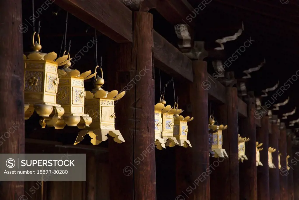 Row of golden japanese metal lanterns hanging in a temple, kyoto, japan