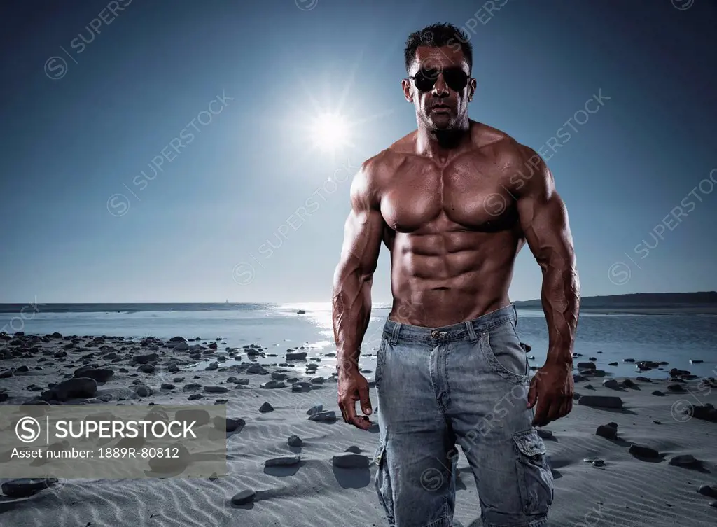 Portrait of a muscular man standing on a beach in sunglasses, tarifa cadiz andalusia spain