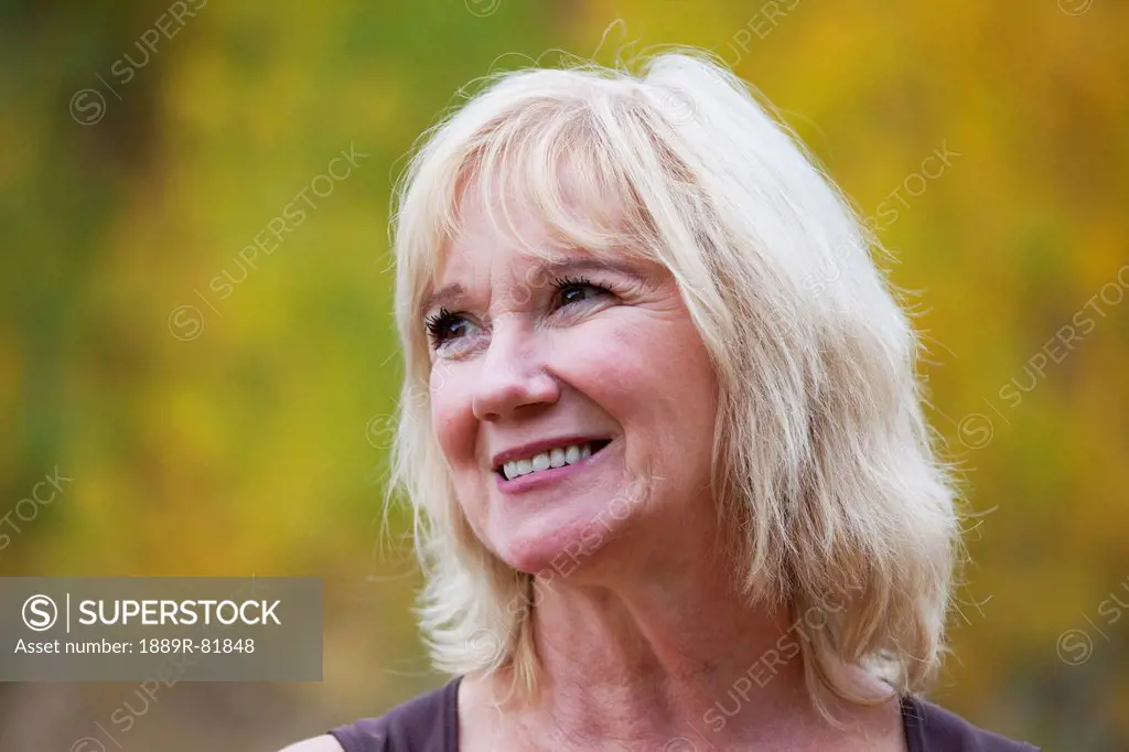 Portrait of a mature woman smiling in a park with autumn colours, edmonton, alberta, canada