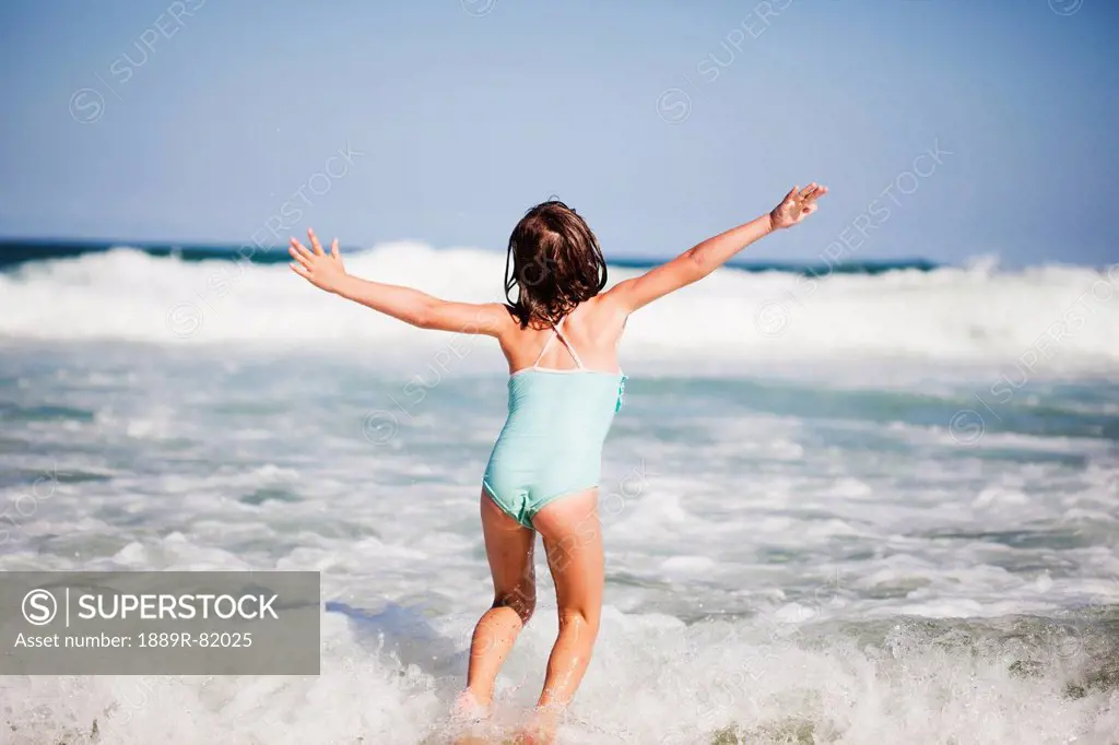 A young girl plays in the waves of the ocean, gold coast, queensland, australia