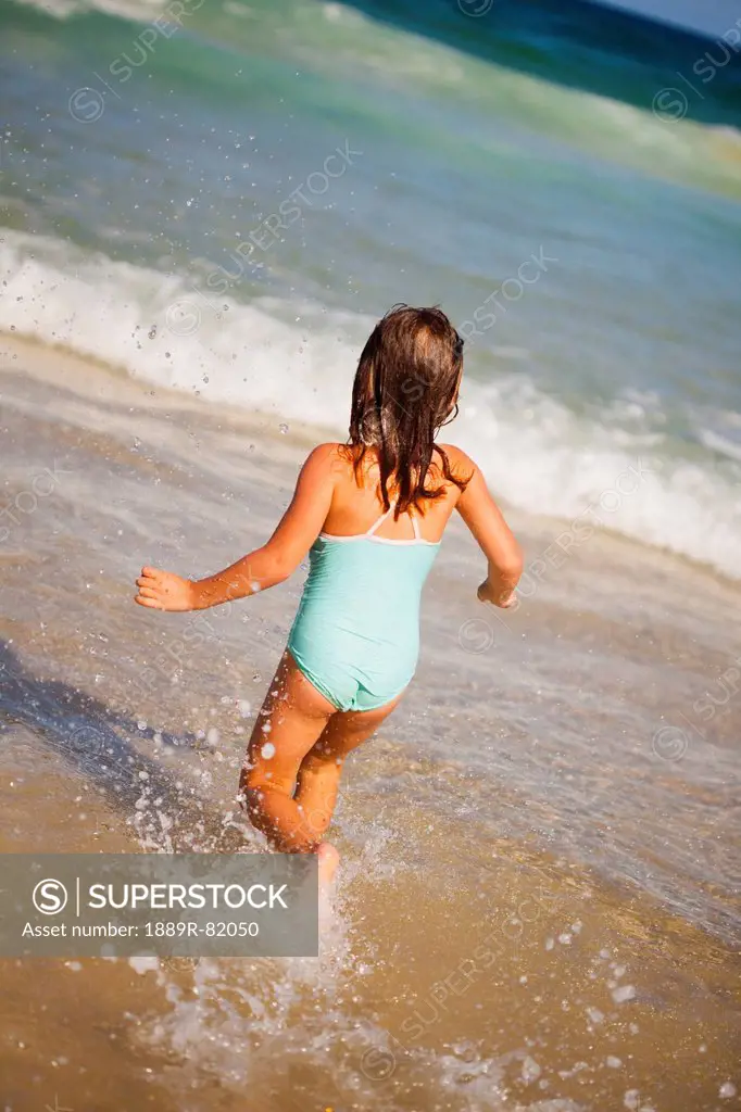 A young girl runs in the ocean from the beach, gold coast queensland australia