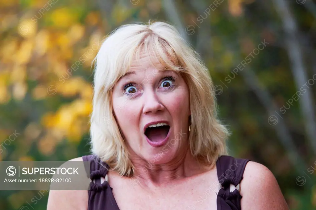 Mature woman surprised in a park with autumn colours, edmonton, alberta, canada