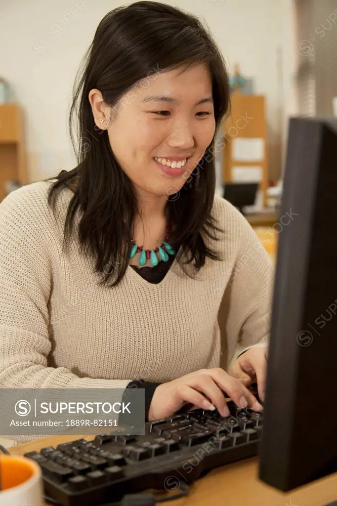 Woman working at a computer on a desk, beijing, china