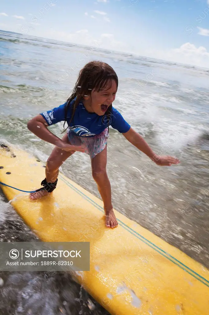 A young girl on a yellow surfboard, gold coast queensland australia