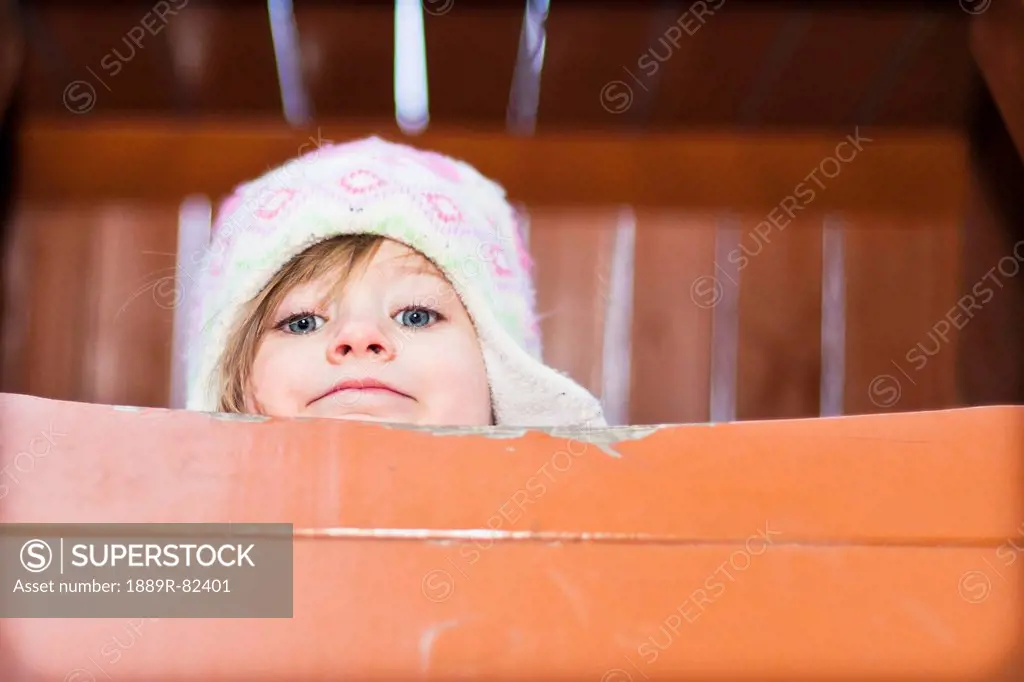 A young girl peeks over edge of playground equipment, beijing, china