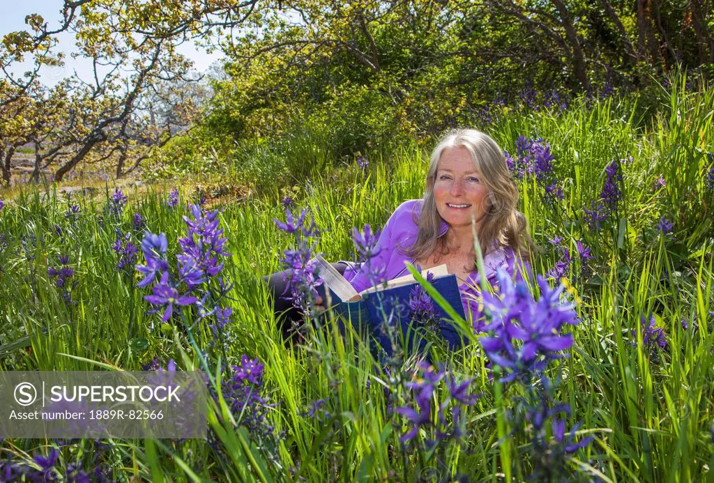 A senior woman reads in a sea of camassia, victoria british columbia canada