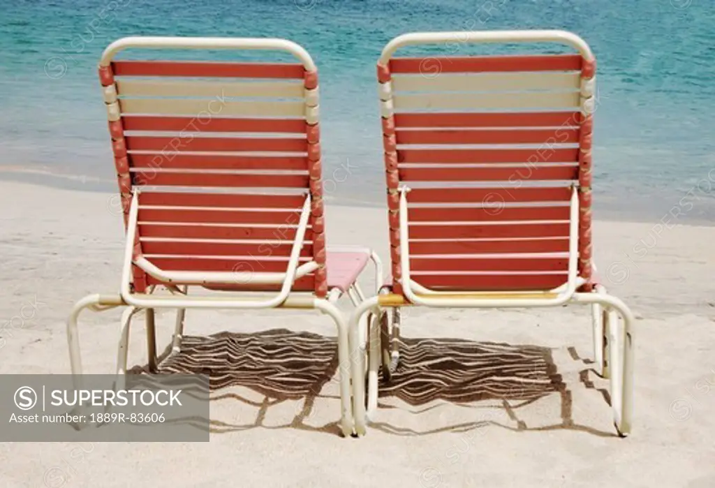 Two pink lounge chairs on a white sand beach, cane garden bay tortula british virgin island