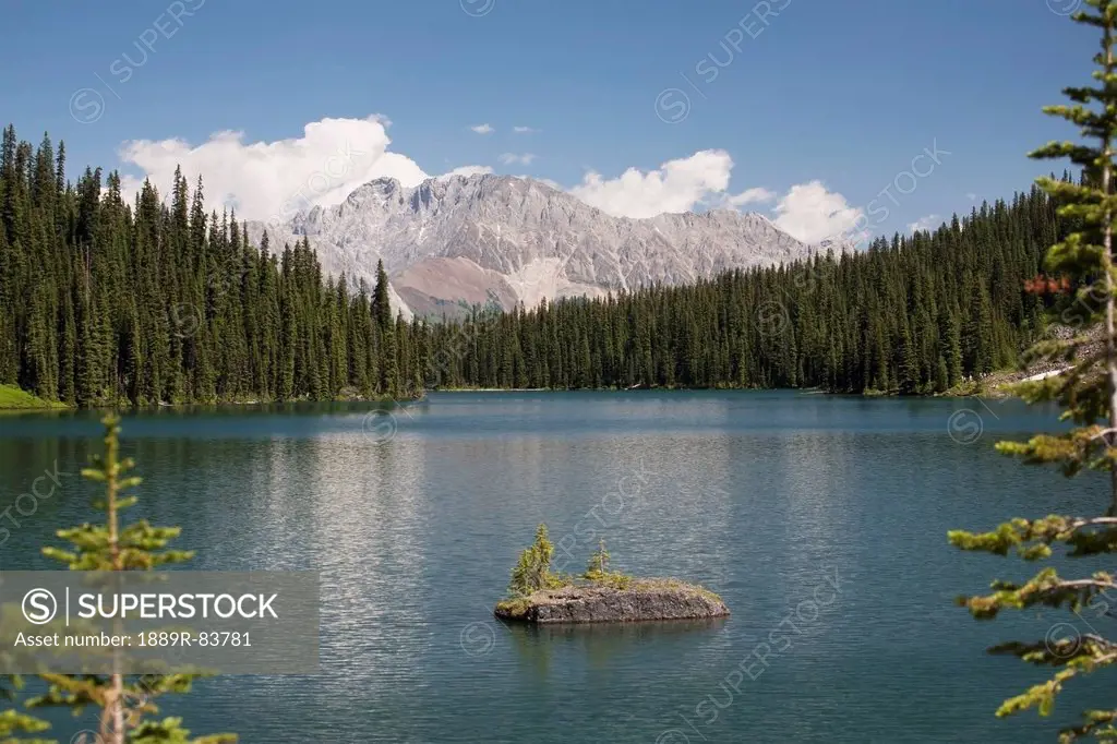 Mountain Lake With Mountain In The Background Framed By Trees With Blue Sky And Clouds In Kananaskis Provincial Park, Alberta Canada