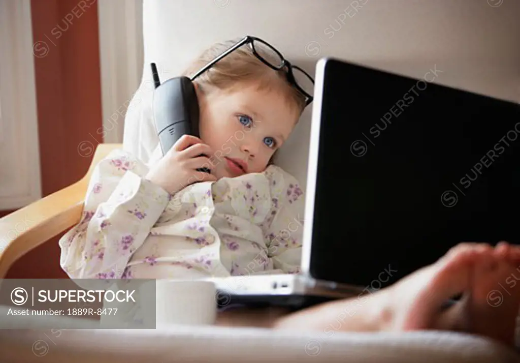Child working on phone and computer