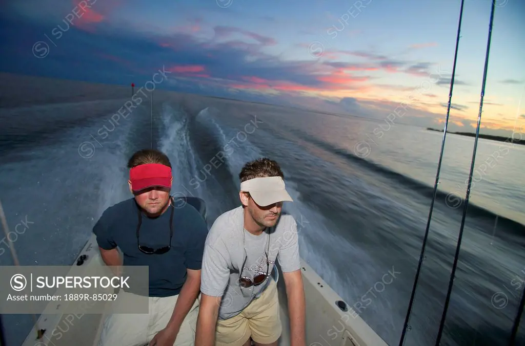 Men riding on a boat at sunset, north carolina united states of america