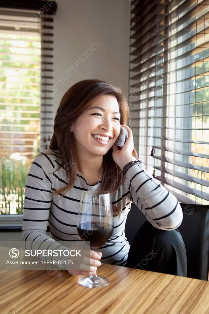 A young woman talking on the phone while holding a glass of wine, berkeley california united states of america