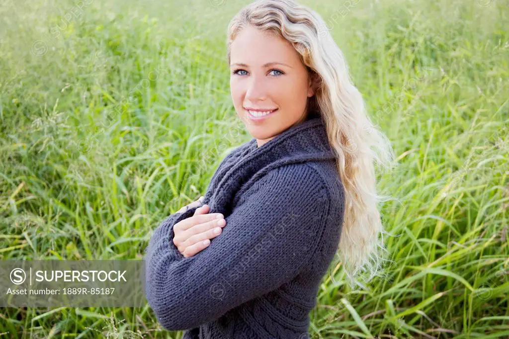 Portrait of a young woman standing in a grass field, hawaii united states of america