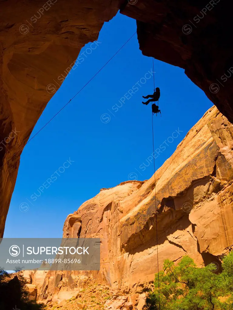 A Female Athlete Rappeling Down A Dry Utah Slot Canyon Waterfall, Hanksville Utah United States Of America
