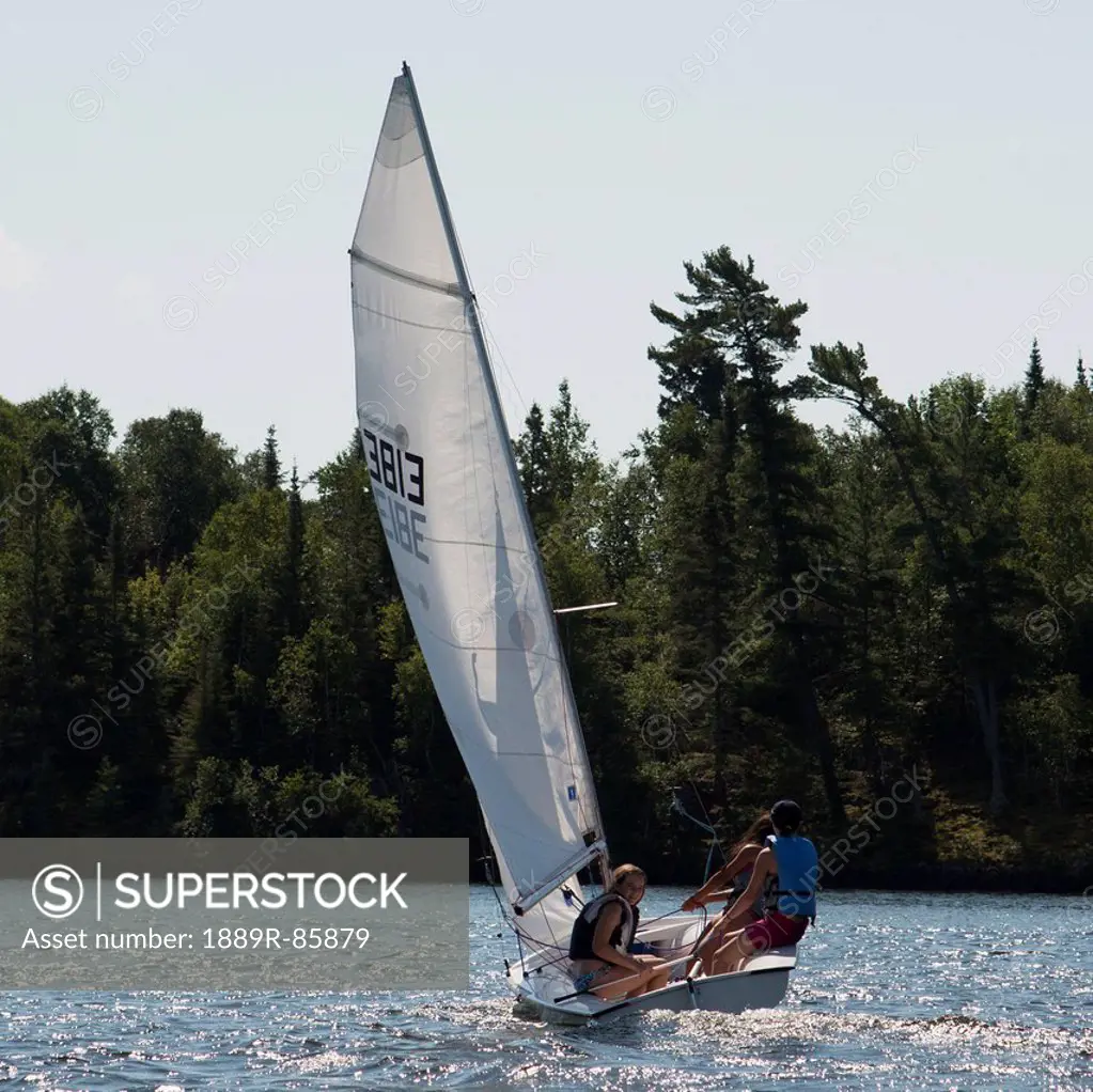 Three Teenagers On A Sailboat In A Lake, Kenora Ontario Canada