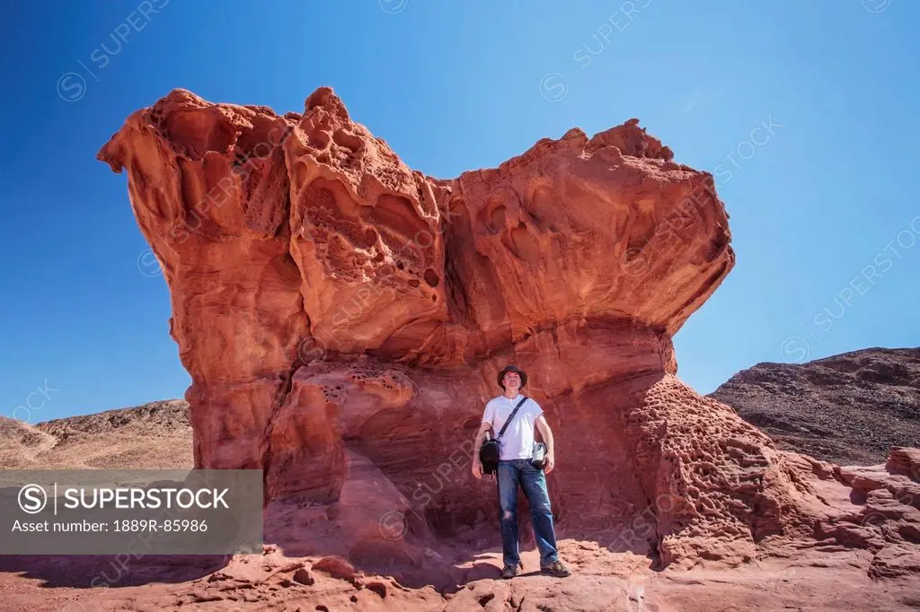 A Man Stands Under A Large Rock Formation, Timna Park Arabah Israel