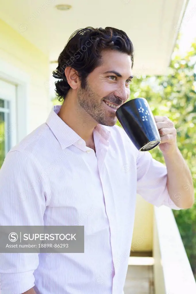 A Man Drinking A Cup Of Coffee On A Balcony;Wailua Kauai Hawaii United States Of America