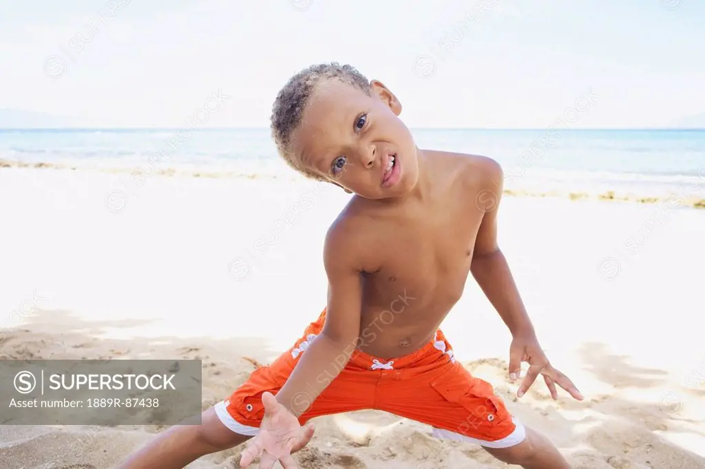 A Young Boy Poses With A Silly Face While Standing In The Sand By The Ocean;Hawaii United States Of America