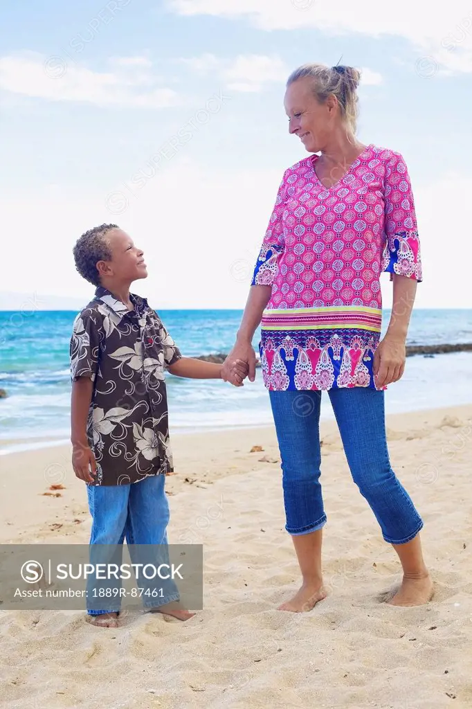 A Mother And Son Standing In The Sand At The Water's Edge;Hawaii United States Of America