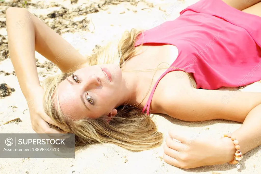 A Teenage Girl In A Pink Dress Laying In The Sand;Maui Hawaii United States Of America
