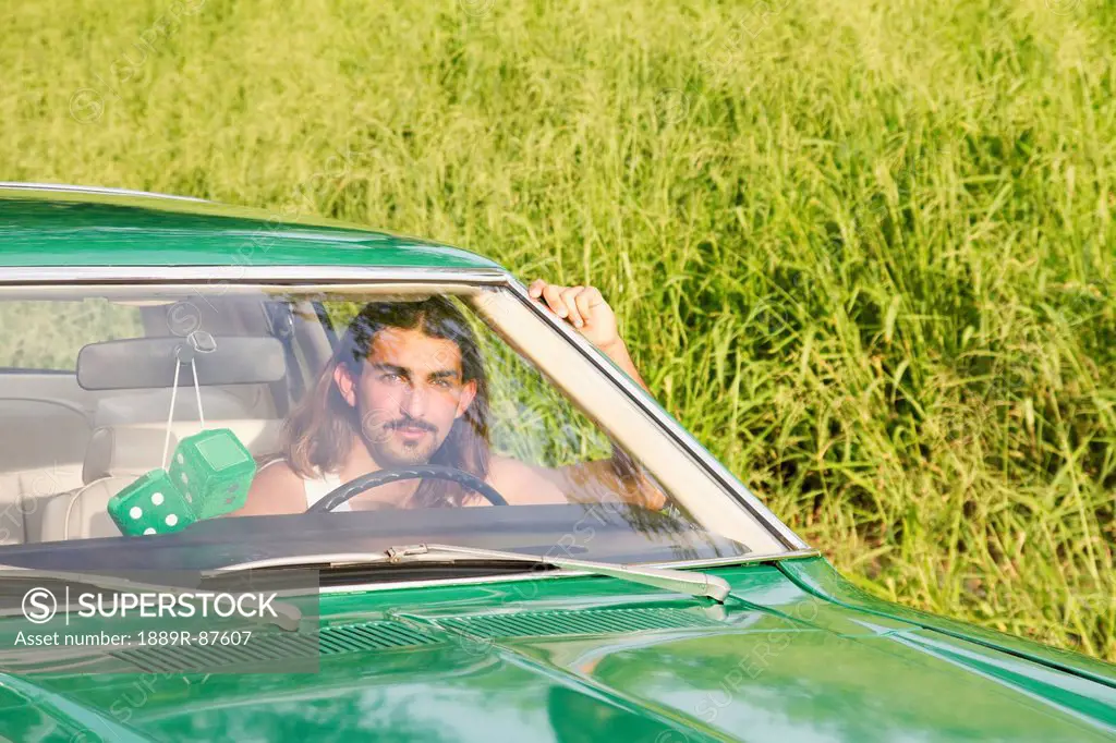 A Young Man Drives A Green Vintage Car With Green Fuzzy Dice Hanging From The Rearview Mirror;Hawaii United States Of America