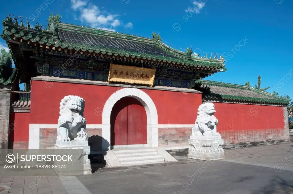 Lion Statues Outside A Red Wall And Building With Chinese Architecture In The Hutong Area;Beijing China