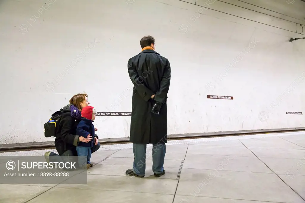 A father mother and young son wait for the max train at the underground washington park stop (zoo);Portland oregon united states of america