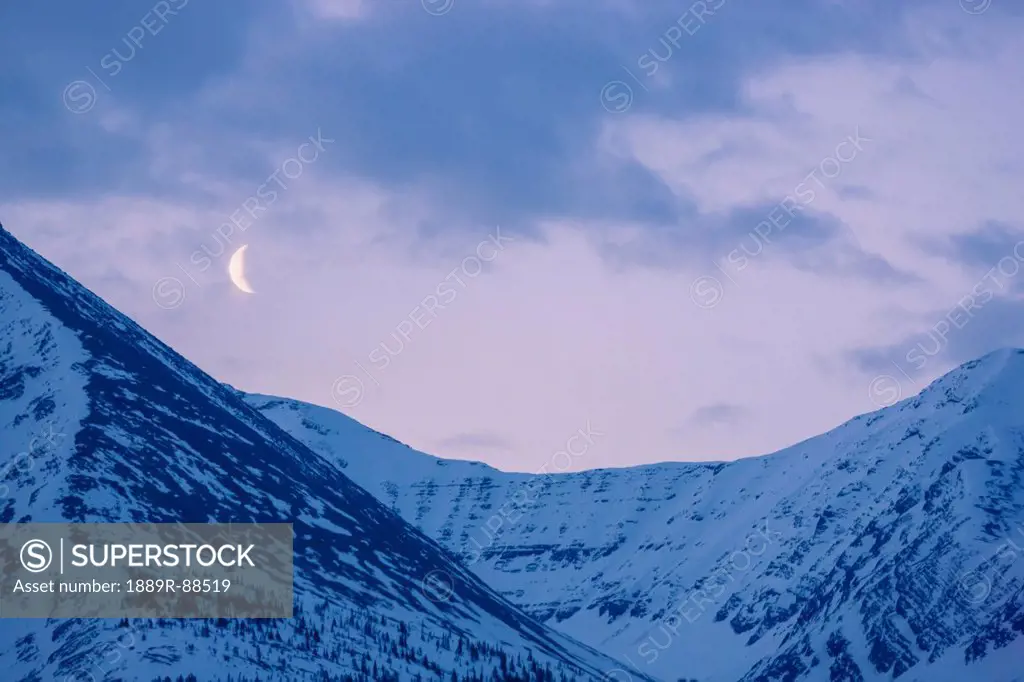 The crescent moon sets above the sentinel range along the alaska highway muncho lake provincial park northern canadian rockies;British columbia canada