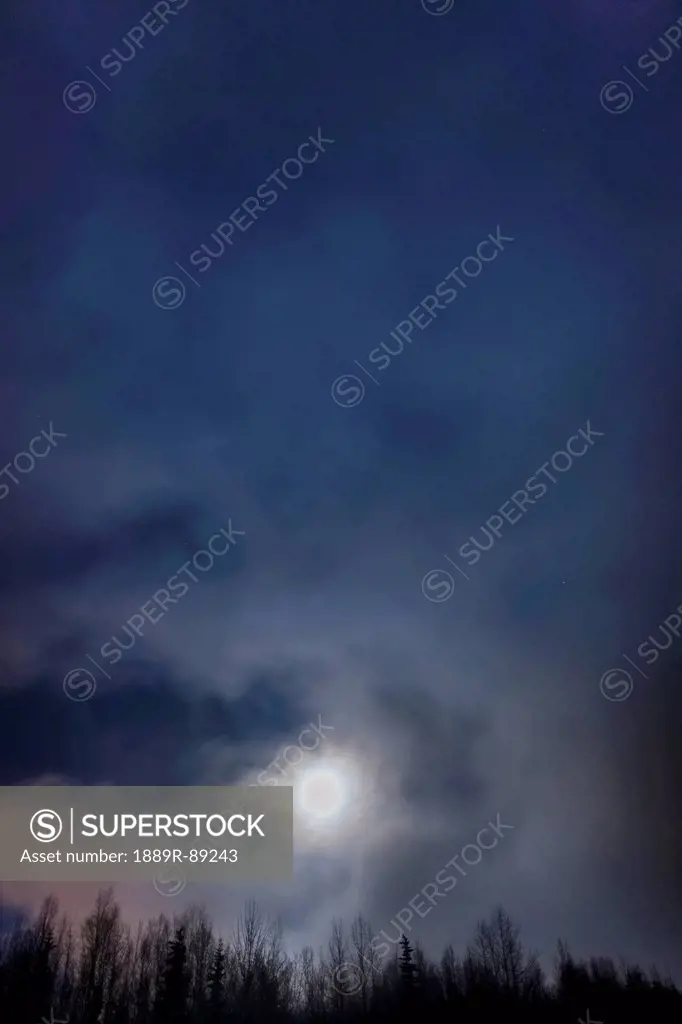 The full moon sets through the fog above the tony knowles coastal trail in winter at nighttime;Anchorage alaska united states of america