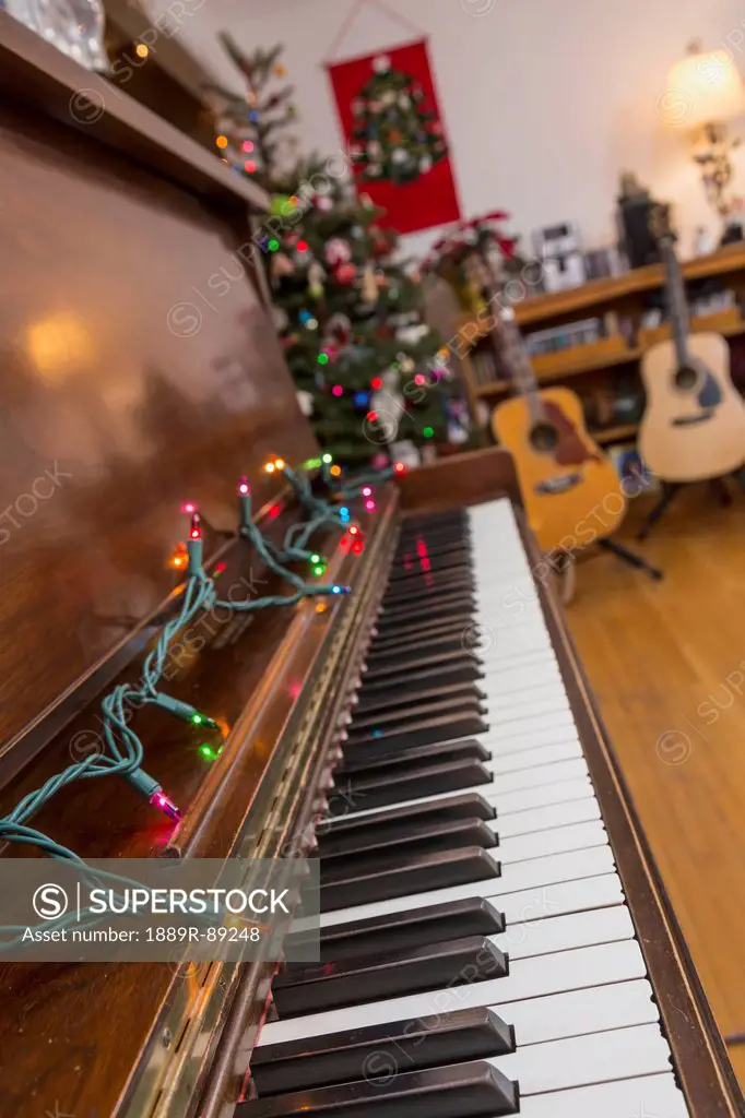 A piano decorated with christmas lights with guitars on stands in the background;Anchorage alaska united states of america