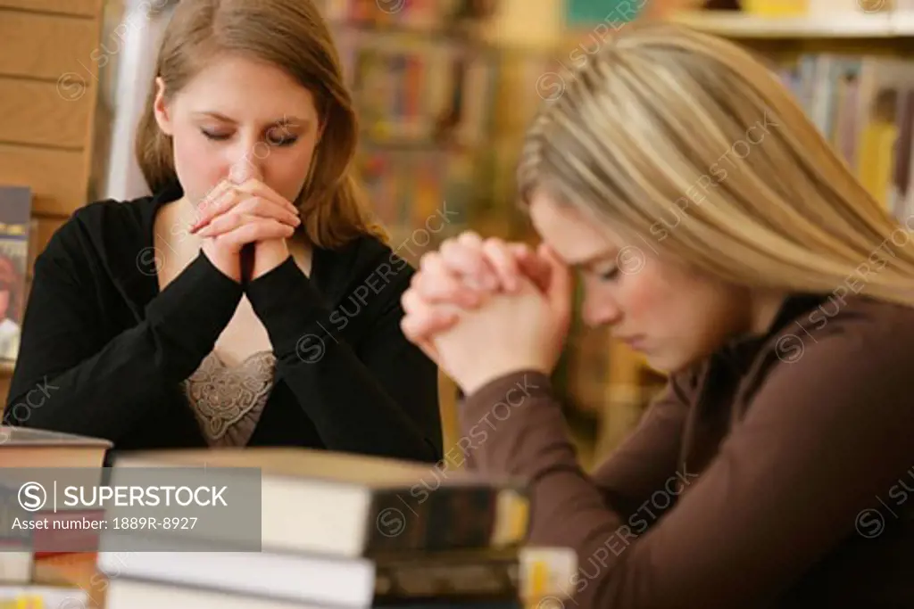 Two women praying in library