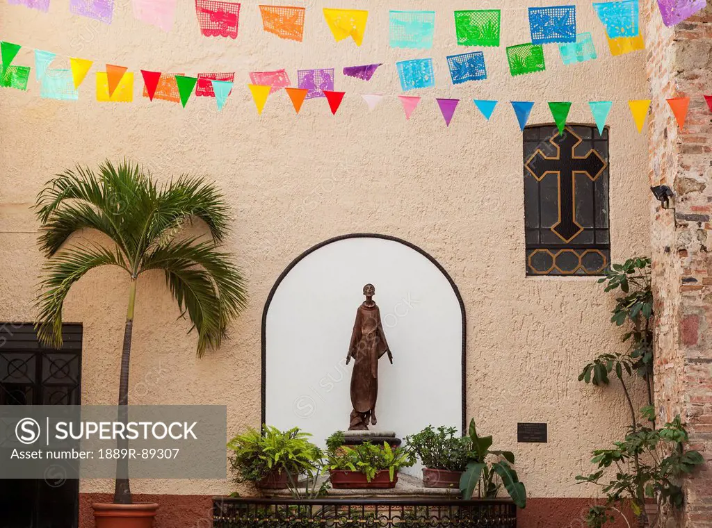 A sculpture of san francisco de assisi is sheltered by the church of our lady of guadalupe;Puerto vallarta mexico