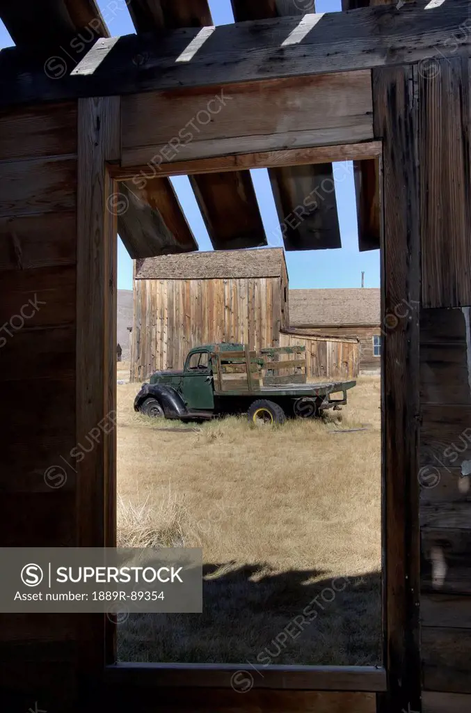 Gold mining ghost town and old truck framed through window of barn;Bodie california united states of america